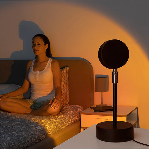 Donna in relax e meditazione con lampada proiettore tramonto in camera da letto, atmosfera romantica e rilassante per benessere